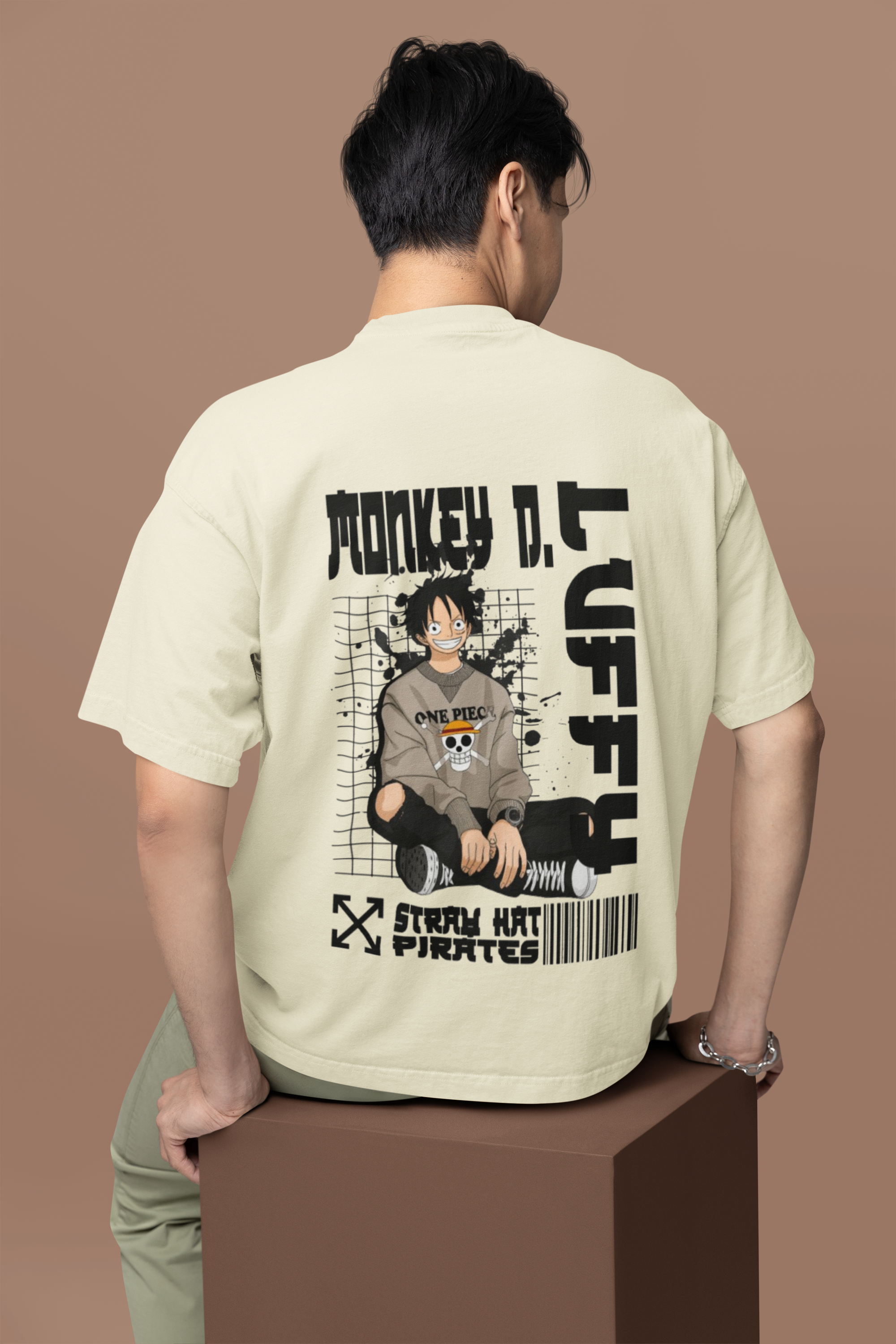 Person wearing a beige t-shirt with a graphic design on the back, standing against a brown background.